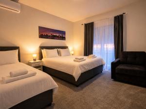 a hotel room with two beds and a chair at Apartments Miš in Trebinje