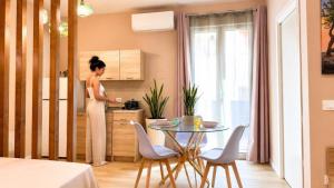 a woman standing in a kitchen with a table at Almantra Rooms - Valle dei Templi e Mare in Favara