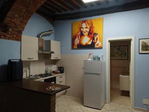 a kitchen with a refrigerator and a painting on the wall at La grotta nel borgo in Roccastrada +17 photos