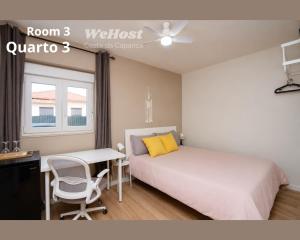 a bedroom with a bed and a desk and a window at We Host Costa da Caparica in Costa da Caparica