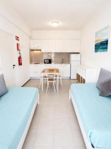 two beds in a room with a kitchen and a table at Apartamentos Central in Quarteira
