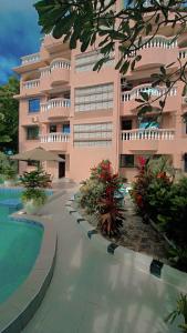 a large pink building with a swimming pool in front of it at EBENEZER Apartment in Diani Beach