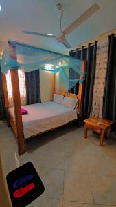 a bedroom with a bed with a canopy and a table at EBENEZER Apartment in Diani Beach