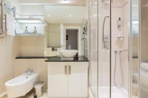 a white bathroom with a sink and a shower at Beaufort House - Knightsbridge in London +113 photos