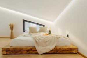 a bedroom with a white bed with a bottle of wine on a wooden platform at Monside Resort - FIRE CABIN in Borzont