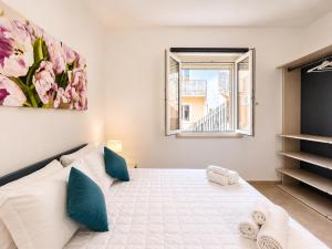 a bedroom with a large bed with blue pillows and a window at Corte Dei Fiori Acquaviva Apartments in Marittima
