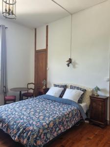 a bedroom with a bed with a blue comforter at Chateauneuf in Sadirac