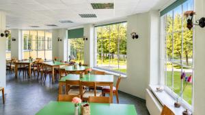 a restaurant with tables and chairs and large windows at Paide Event Center Hostel in Prääma