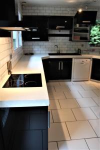 a kitchen with black cabinets and white tile floors at Ma chaumiere in Les Cammazes