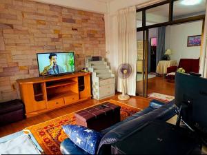 a living room with a couch and a tv at Phafan pool villa in Ban Pa Sang (1)