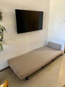 a couch with a flat screen tv on a wall at Cosy Sunnyland, accès direct plage et parking privatif in La Grande Motte +18 photos