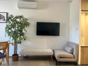 a living room with a couch and a tv on the wall at Cosy Sunnyland, accès direct plage et parking privatif in La Grande Motte