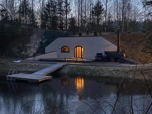 a small white building with a window next to a body of water at Rabbit Hole Hotel in Laiksaare