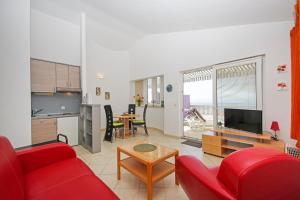a living room with a red couch and a kitchen at Apartmani Villa Antonio in Makarska