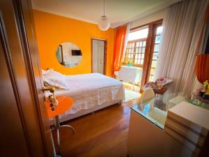 a bedroom with orange walls and a bed and a mirror at Estadia Diamantes in Diamantina