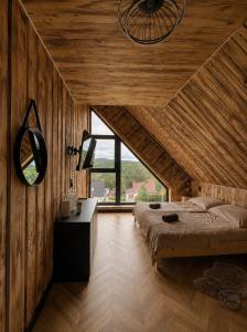 a bedroom with wooden walls and a bed and a mirror at Przystań Ukoya in Koniaków