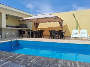 a patio with a table and umbrella next to a pool at La Ruta in Paracas