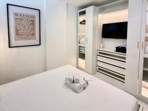 a white bedroom with a bed and a tv at Le Soleil Tropézien, Somptueux 2 pièces - Terrasse Vue Mer in Menton