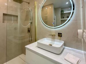 a bathroom with a sink and a shower with a mirror at Le Soleil Tropézien, Somptueux 2 pièces - Terrasse Vue Mer in Menton +30 photos