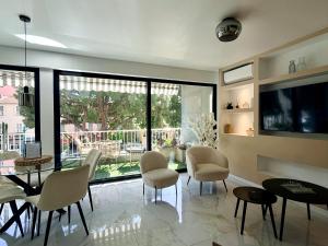 a living room with a table and chairs and a television at Le Soleil Tropézien, Somptueux 2 pièces - Terrasse Vue Mer in Menton