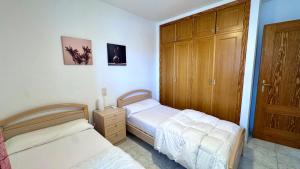 a bedroom with two beds and a wooden cabinet at Talima Vyb Dénia in Denia +40 photos