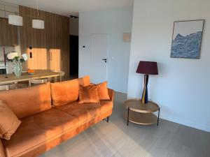 a living room with a brown couch and a table at SolMarina Apartment for Rent in Wiślinka +3 photos