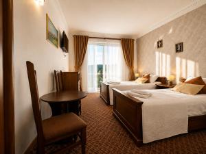 a hotel room with two beds and a table at Hotel Three Korony in Skhidnitsa
