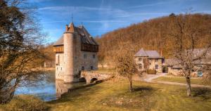 a castle on a river with a bridge at Private spa - La Sparenthèse in Ciney