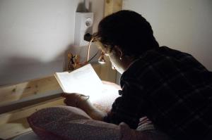 a man reading a book on a bed at Lua Lua Hostel Las Palmas in Las Palmas de Gran Canaria