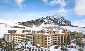 a hotel in the snow with a mountain in the background at The Grand Lodge, A Vail Resorts Property in Mount Crested Butte