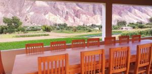 a table with chairs and a large window with mountains at La Posta de Gherard in Maimará