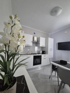a kitchen with white cabinets and a vase with white flowers at Stornelli Suite & Apartments in Avezzano