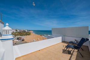 a balcony with two chairs and a lighthouse on the beach at Vista del Mar Guest House in Albufeira