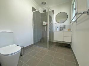 a bathroom with a shower and a toilet and a mirror at Brownies on Birch in Amity Point +8 photos