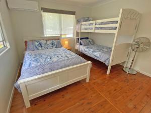 a bedroom with two bunk beds and a fan at Brownies on Birch in Amity Point