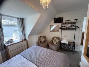 a bedroom with a bed and a chair and a chandelier at Glendale Guesthouse in Oban