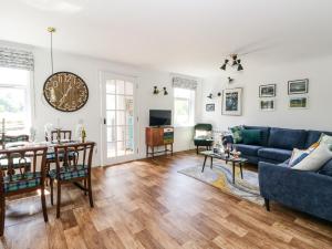 a living room with a blue couch and a clock on the wall at Kilmartin View in Lochgilphead
