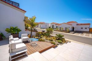 a patio with white chairs and a table and some houses at Villa Coral 3 BR 3BA with pool in Primo Tapia +28 photos