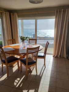 a dining room with a table and chairs and a large window at Ballyheigue Cliff Side and Sea View Apartment in Ballyheigue