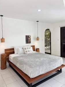 a bedroom with a large bed with white walls at Encantador Loft con Piscina 1 BDR in Santa Teresa Beach