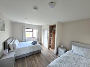 a white bedroom with two beds and a window at Tigh Fitz Apartments - Inis Mór, Aran Island in Inis Mor
