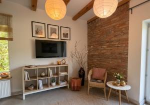 a living room with a tv and a brick wall at Siedlisko Dębinka in Miłomłyn