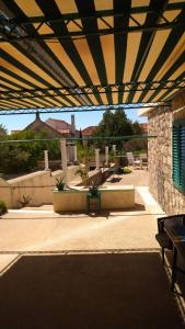 a patio with a roof with a table and benches at Studio apartman Marija 2 in Bol