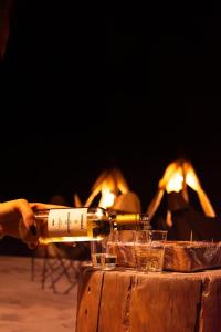 a person pouring a bottle of wine in front of a fireplace at Duna Camp Huacachina in Ica