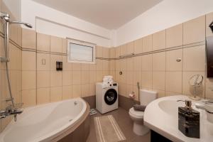 a bathroom with a tub and a washing machine in it at Captain's Corner in Markopoulo +41 photos