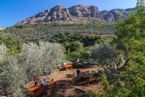 a group of people sitting at tables in front of a mountain at My Olive Garden Camp in Bar