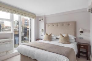a white bedroom with a large bed and a window at Beaufort House - Knightsbridge in London