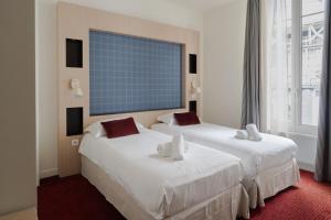 two beds in a hotel room with a window at Marnie House in Le Touquet-Paris-Plage