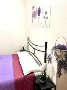 a bedroom with a bed with purple sheets and flowers at Le Saliscalette in Norcia