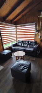 a living room with a black couch and a table at Cabañas Maullin in Maullín